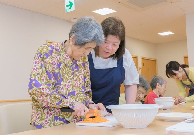 画像：食事を作る入居者と職員