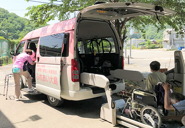 画像：手を上げてリハビリをする職員と入居者